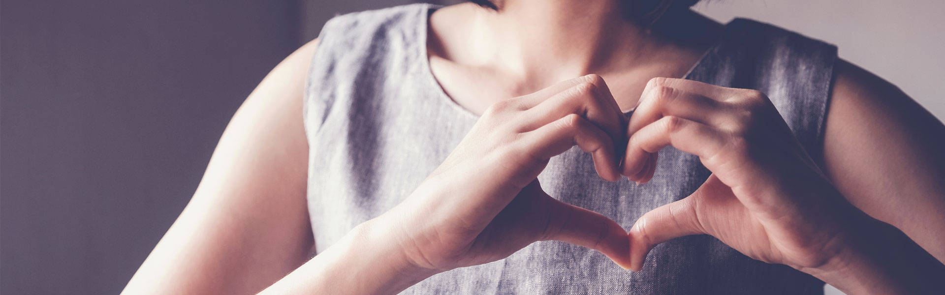 young woman holding her hands in a heart shape