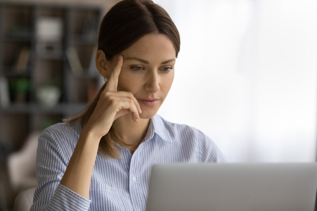 Woman looking thoughtfully at computer screen