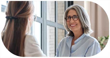 image for finding talent in customer centric recruitment showing two female executives smiling and chatting in an office environment 